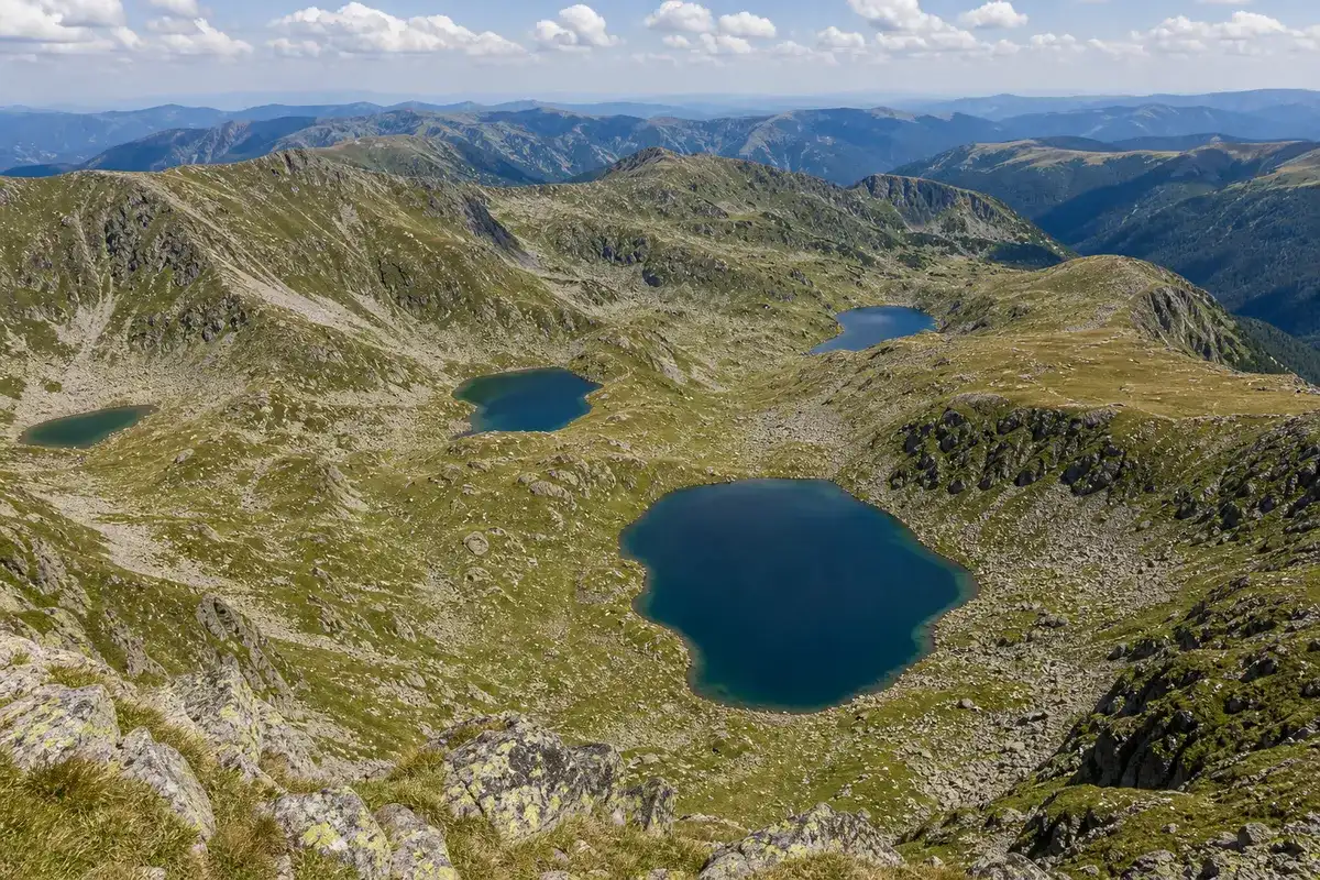 Mai multe lacuri glaciare mici văzute de pe creastă în căldările Parângului