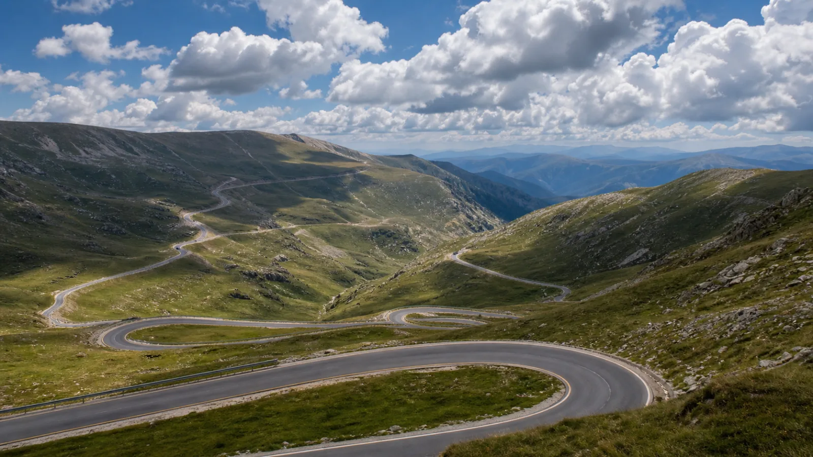 Drum alpin de mare altitudine șerpuind printre culmi verzi pe Transalpina, vara